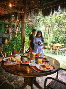 Um homem e uma mulher à volta de uma mesa com comida. em Eco Quechua Lodge em Santa Teresa