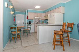 a kitchen with blue walls and wooden chairs at Seaspray in Atlantic Beach
