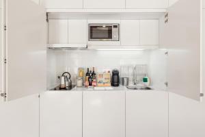 a kitchen with white cabinets and a microwave at Stay in the heart of Porto! in Porto