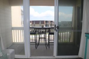 una puerta corredera de cristal con un balcón con una mesa en A Place At The Beach V en Atlantic Beach