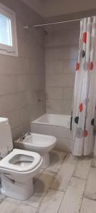 een badkamer met een toilet, een bad en een wastafel bij Cabañas Boutique Los Cipreses in Villa Ventana