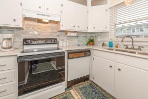 a kitchen with white cabinets and an oven and a sink at Pine Knoll Townes in Pine Knoll Shores