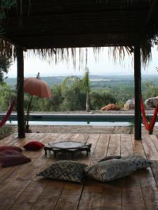 un patio con almohadas en una terraza de madera con sombrilla en Casa las Marias, en Hornachuelos