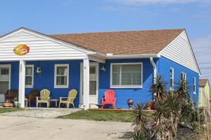 una casa azul con sillas coloridas delante en Toes In The Sand, en Atlantic Beach