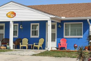a blue house with colorful chairs in front of it at Toes In The Sand in Atlantic Beach
