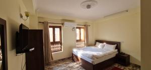 una camera con letto, TV e finestre di Pashupati View Hotel a Kathmandu