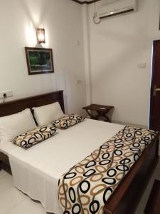 ein Schlafzimmer mit einem Bett mit einer braunen und weißen Bettdecke in der Unterkunft Villa seaside in Bentota