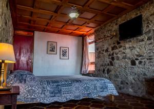 a bedroom with a bed and a stone wall at Hotel Terrazas Del Lago in San Antonio Palop&oacute;