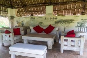 a room with a couch and two tables and chairs at Amani Paradise - Luxury Villas in Diani Beach