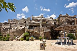 a large stone building with an umbrella in front of it at Artemis Apartments in Tinos