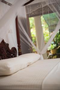 Bett mit Kissen in einem Zimmer mit Fenster in der Unterkunft Alice in Paradise in Unawatuna