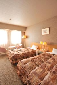 a hotel room with two beds and a window at Rako Hananoi Hotel in Suwa