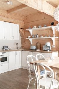 a kitchen with white cabinets and a wooden wall at Śnieżna Dolina - Sobiczkowa Bór Luxury Chalets in Kościelisko