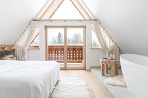 1 dormitorio con cama, bañera y ventana en Śnieżna Dolina - Sobiczkowa Bór Luxury Chalets, en Kościelisko