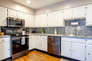 a kitchen with white cabinets and stainless steel appliances at Heart of the Old City- Minutes from Market Square in Knoxville