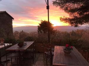 einen Holztisch und Stühle mit Sonnenuntergang im Hintergrund in der Unterkunft Malvarina in Capodacqua