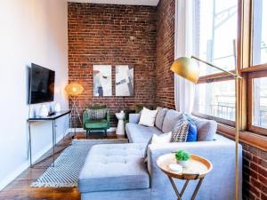 uma sala de estar com um sofá azul e uma parede de tijolos em Modern Old City Loft - Downtown Knoxville em Knoxville