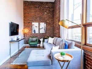 a living room with a blue couch and a brick wall at Modern Old City Loft - Downtown Knoxville in Knoxville