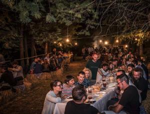 eine Gruppe von Menschen, die nachts an langen Tischen sitzen in der Unterkunft Malvarina in Capodacqua