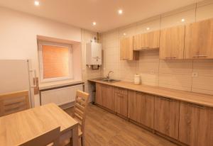 a kitchen with wooden cabinets and a sink and a table at Apartamenty ZYGFRYD 28C/1 in Bystrzyca Kłodzka