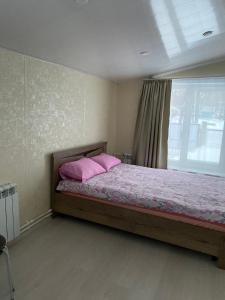バイカリスクにあるBerezovy Guest Houseのベッドルーム1室(ピンクの枕が付くベッド1台、窓付)