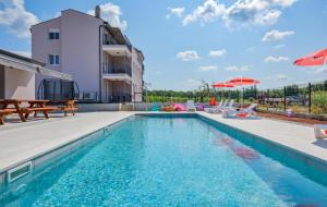 a swimming pool with chairs and umbrellas next to a building at Apartmani Lucija in Poreč