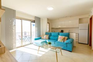 a living room with a blue couch and a kitchen at Solen Suites Arguineguin in Arguineguín