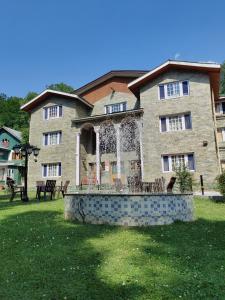 a large brick building with a porch in the yard at Hotel Outlook - Pahalgam in Pahalgām