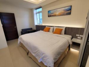 a bedroom with a large white bed with orange pillows at 綠堤泰安民宿 in Taitung City