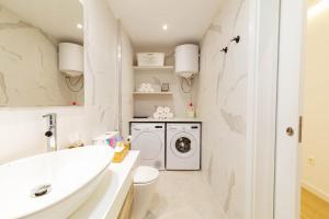 baño blanco con lavadora y lavamanos en Apartamentos Deluxe Strada, en Las Palmas de Gran Canaria