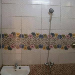 a bathroom with a sink and a shower with flowers on the wall at Abu Omair Jabal Shams House in Al Ḩamrāʼ