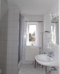 a white bathroom with a sink and a window at Feddersen's Ferienwohnung in Harrislee