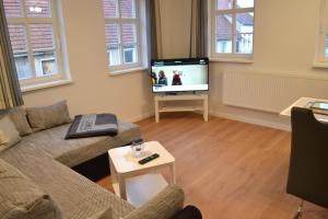 a living room with a couch and a tv at Ferienwohnungen im alten Pfarrhaus in Eisenach