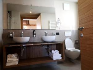 a bathroom with two sinks and a toilet and a mirror at Garni Al Silvestri Vei in Livigno