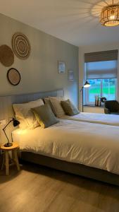 um quarto com uma grande cama branca e uma janela em De Logeerkamer Gapinge em Gapinge