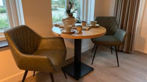 a table with two chairs and a table with cups on it at De Logeerkamer Gapinge in Gapinge