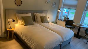 a bedroom with a large white bed with a window at De Logeerkamer Gapinge in Gapinge