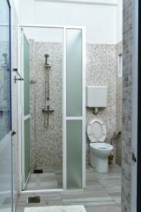 een badkamer met een toilet en een glazen douche bij Nature Lanka Guest House in Negombo