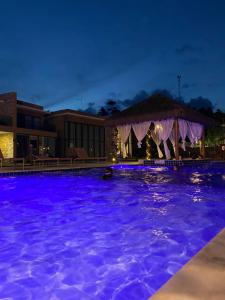 una piscina notturna con luci viola di Condomínio Morada do Toque - Casa 08 a São Miguel dos Milagres