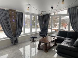 a living room with a couch and a table and windows at Вілла Смерекова хата - Келечин 144 in Pilipets