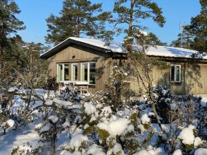 een klein huis met sneeuw op de grond bij Ljugarnsstugor in Ljugarn