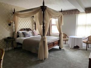 a bedroom with a canopy bed with curtains and a table at The Sitwell Arms Hotel in Mosborough