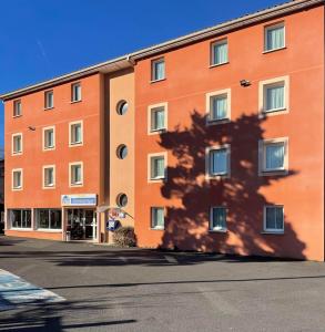 a large orange building with a shadow on the side of it at Deltour Hotel Le Puy En Velay in Le Puy-en-Velay