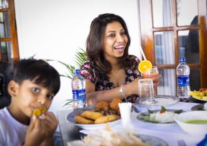 a woman sitting at a table with a boy eating food at Villa Sole in Kandy