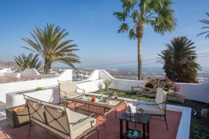 a patio with chairs and tables and palm trees at Villa Atlantis I in La Asomada