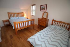 a bedroom with two beds and a dresser and a mirror at SeaSpray Cottage in Rathmullan