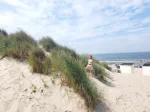 Una mujer caminando por la hierba en una playa en Beachhouse Renesse 2645 en Renesse