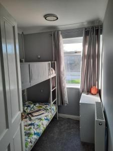 a small room with a bunk bed and a window at Cosy 3 bedroom residential house, private garden, 30 minutes from Alton Towers, 5 minute walk to Trentham Gardens. in Stoke on Trent