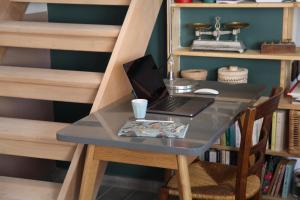 un ordinateur portable assis sur une table à côté d'une étagère dans l'établissement LYONEST chambre d'hôtes, à Lyon