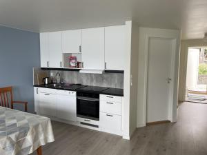 eine Küche mit weißen Schränken und einem Herd mit Backofen in der Unterkunft Fjord Apartments in Dimmelsvik